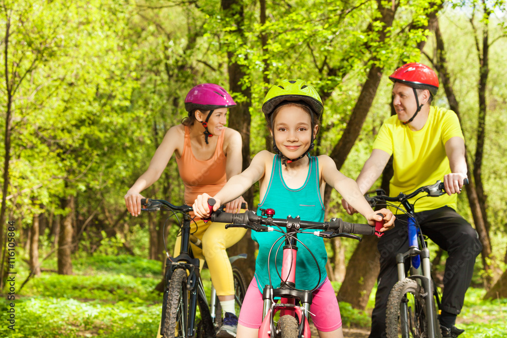 Naklejka premium Happy girl having fun the cycling with her parents