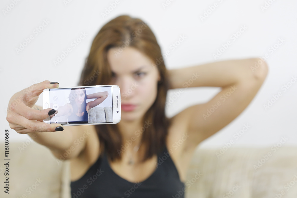 Beautiful young woman photographing herself with phone at home Beautiful young woman photographing herself with phone at home