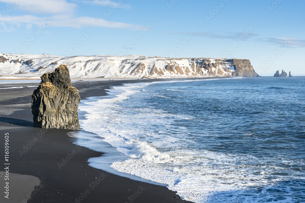 Fototapeta premium Big basalt rock on the Reynisfjara black sand beach, view from Dyrholaey. Vik, South Iceland.