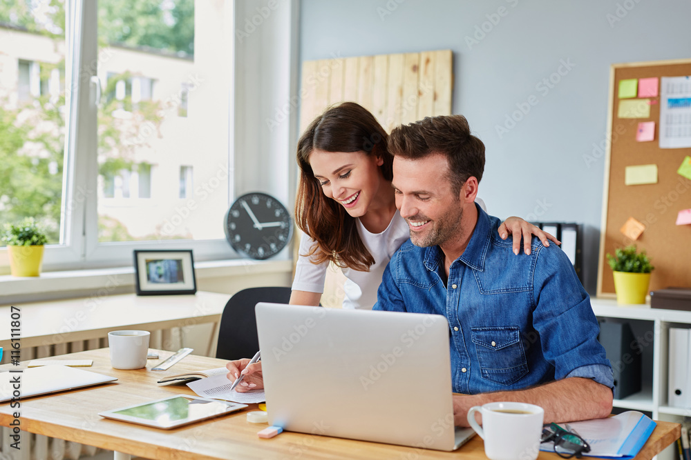 Happy couple doing business together working at small office on Happy couple doing business together working at small office on