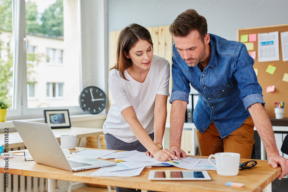 Busy couple working at the office doing business together Busy couple working at the office doing business together
