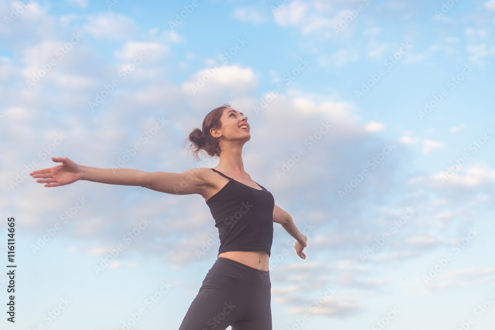 woman enjoying sunset with arms outspread and face raised in sky woman enjoying sunset with arms outspread and face raised in sky