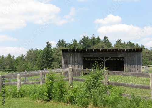 Animal shelter for horses in a fenced meadow.