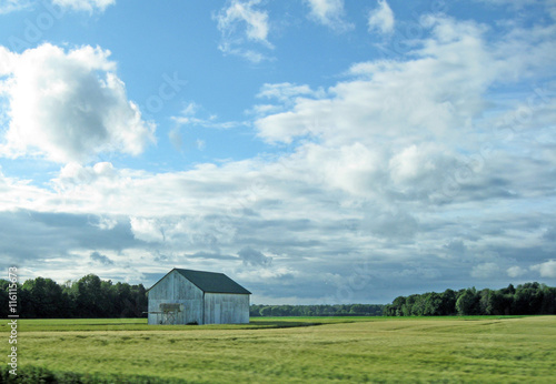 A small grey barn in a farmer's field.