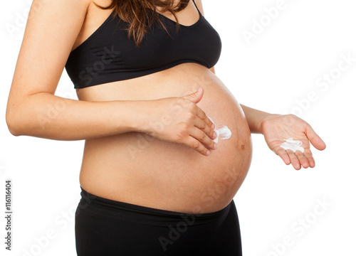 pregnant woman massaging her belly with ointment against stretch