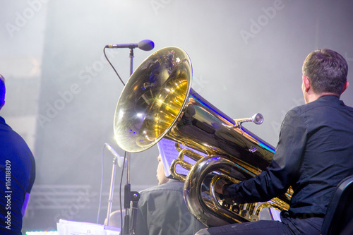 Tubaist in an orchestra on the stage, holds big brass tube, behind the scenes shoot photo