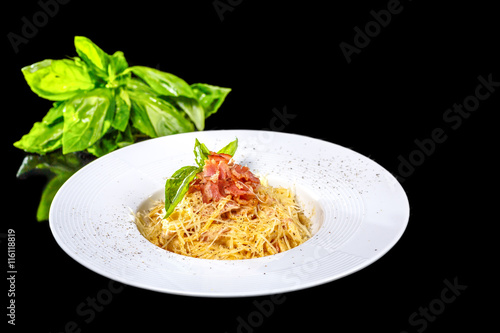 Spaghetti Carbonara with Basil on a black background, isolated.