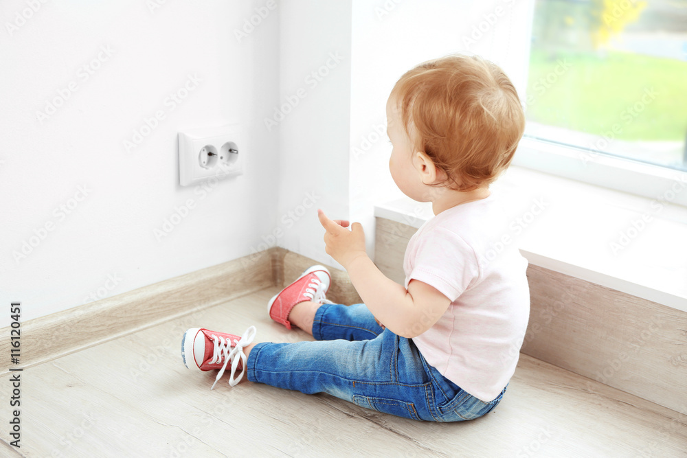 Baby playing with electrical outlet on floor at home Baby playing with electrical outlet on floor at home