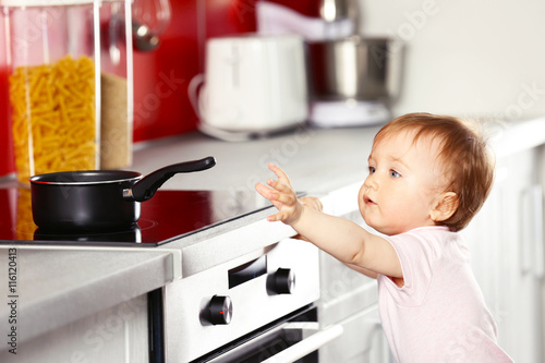 Foto Little child playing with pan and electric stove in the kitchen