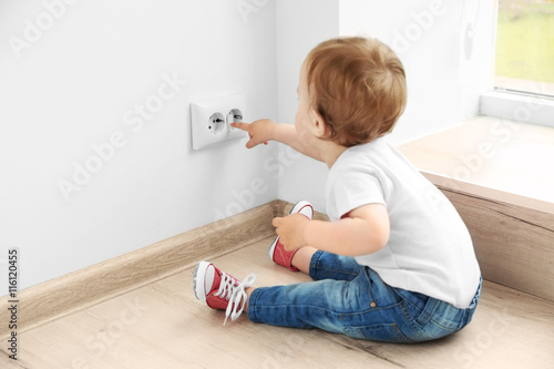 Schilderij op canvas Baby playing with electrical outlet on floor at home
