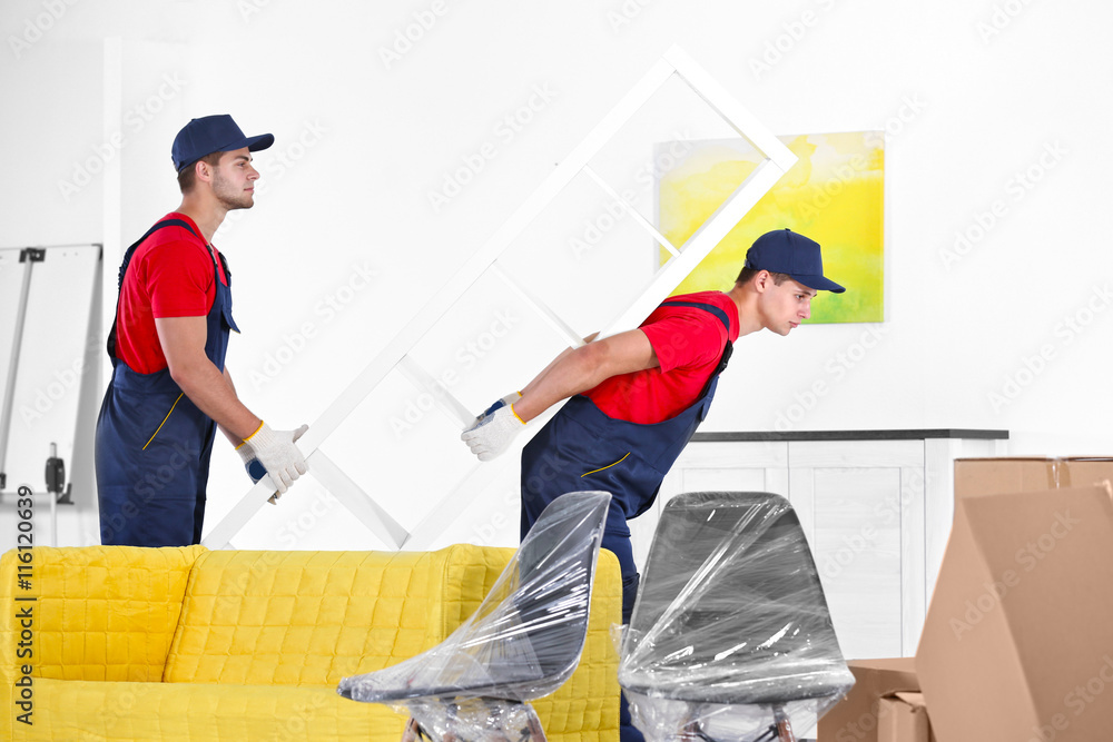 Male workers carrying furniture in new house