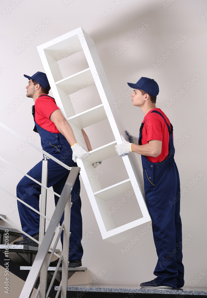 Two male workers with wooden shelves on staircases