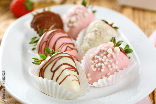 Strawberries covered with different chocolate on white plate
