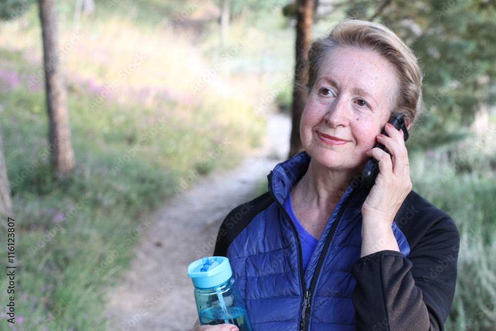 Pretty mature natural woman phoning in the park. Beautiful senior woman with hand on the face Pretty mature natural woman phoning in the park. Beautiful senior woman with hand on the face