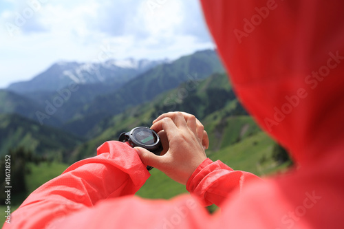 Obraz na plátně young woman hiker checking the altimeter on sports watch at mountain peak