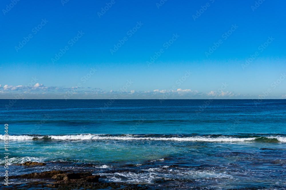 Beautiful ocean surface with moderate surf against blue sky on the background. Cronulla, Australia. Copy space