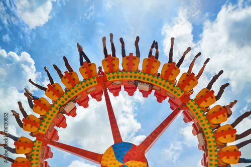 Photo Funny photo of legs of women, men in amusement park riding with fun on extreme attraction swinging upside down high in air on sky background