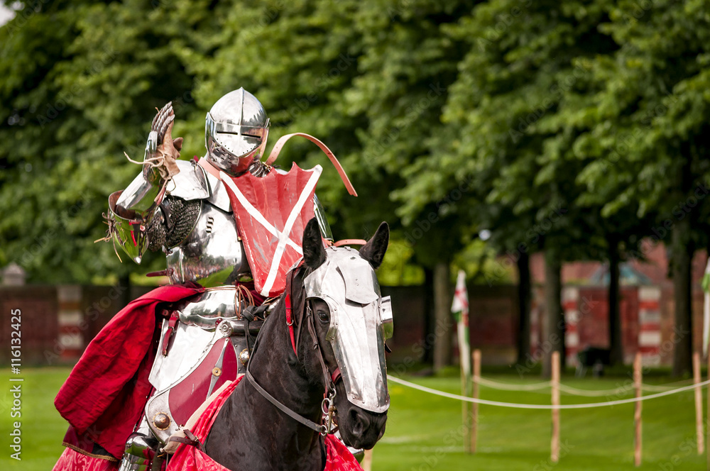 Naklejka premium Armored knight suited for battle on horseback, charging in gallop. Galloping it’s the fastest gait of a horse, and because of the speed the warrior looks even more impressive