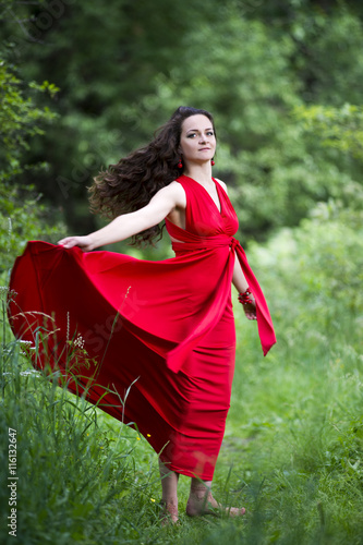 Beautiful young caucasian brunette woman in red dress outdoors