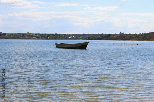 Old fishing boat at anchor in sea near sand shore