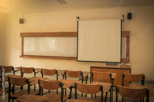 University classroom with desks, blackboard and screen projecter