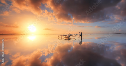 Photographer is taking a picture of sunrise at beach with beautiful sky reflections