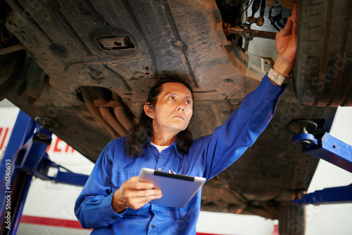 Mechanic using tablet computer when checking car