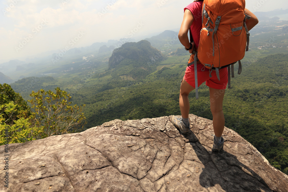 Obraz premium young woman backpacker hiking on mountain peak cliff