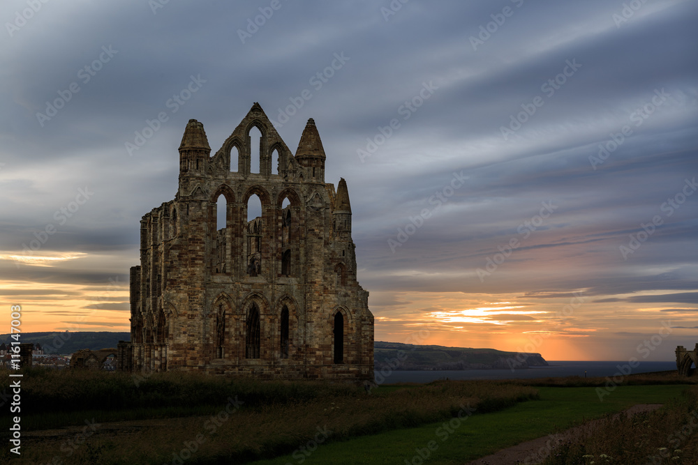 WHITBY, ENGLAND - JULY 16: The ruins of Whitby Abbey against a sunset. In Whitby, North Yorkshire, England. On 16th July 2016. WHITBY, ENGLAND - JULY 16: The ruins of Whitby Abbey against a sunset. In Whitby, North Yorkshire, England. On 16th July 2016.