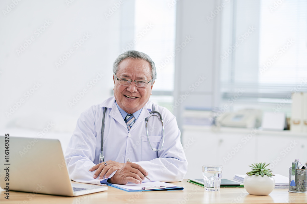 Portrait of aged Vietnamese doctor in his office