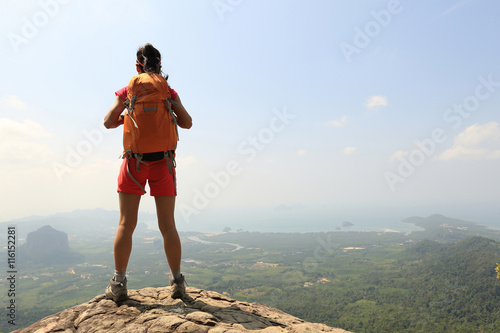successful woman hiker enjoy the view on mountain top rock
