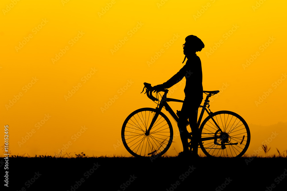 A silhouette of man standing with bicycle