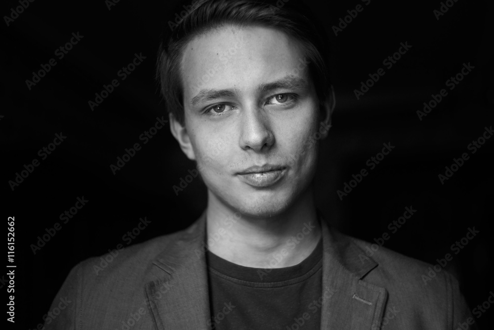 Handsome young man on dark background. Black and white photo Handsome young man on dark background. Black and white photo