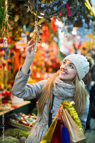 Beautiful young woman choosing Christmas decoration at market photo