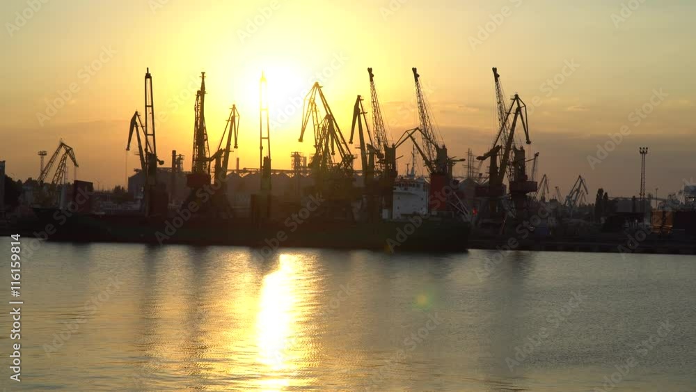 Sunset at the seaport. Wieden ship under unloading, the sun reflected in the Sea Sunset at the seaport. Wieden ship under unloading, the sun reflected in the Sea
