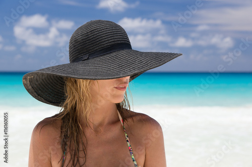 Beautiful blonde woman with black hat, and tropical beach