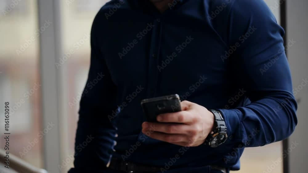 Businessman standing by banisters and calling with walking people on background Businessman standing by banisters and calling with walking people on background
