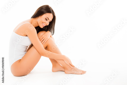 Beautiful brunette in white swimwear touching her foot