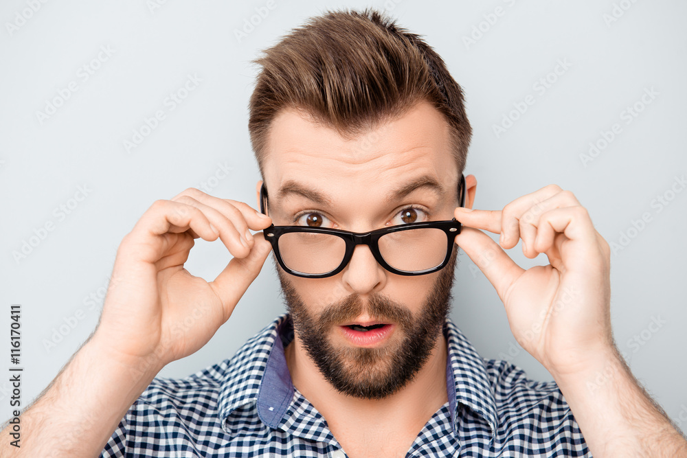 Portrait of shocked modern man touching his spectacles Portrait of shocked modern man touching his spectacles