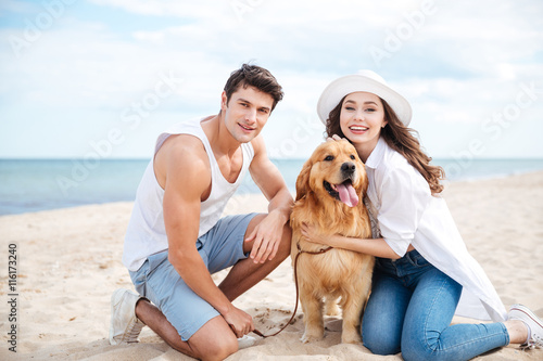 Beautiful young couple with their dog on the beach