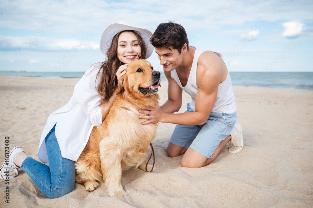 Young couple in love sitting on the beach with dog