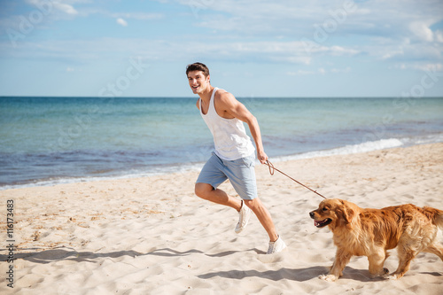 Man running with his dog on the beach