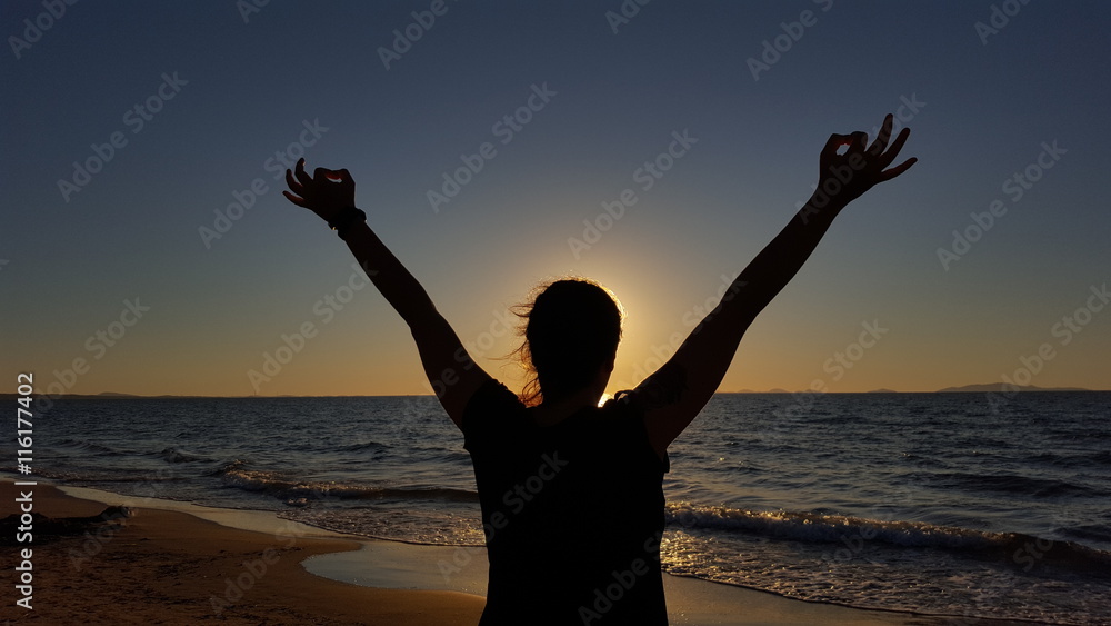 woman with up arms during sunset in the sea summertime