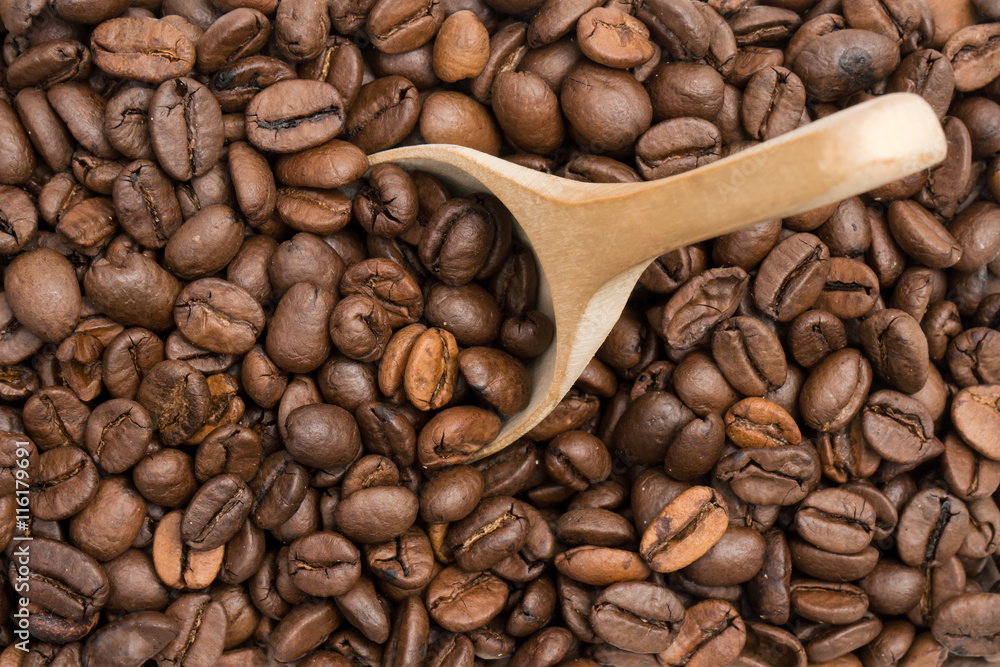 Fototapeta premium Coffee beans with wooden spoon seen from above