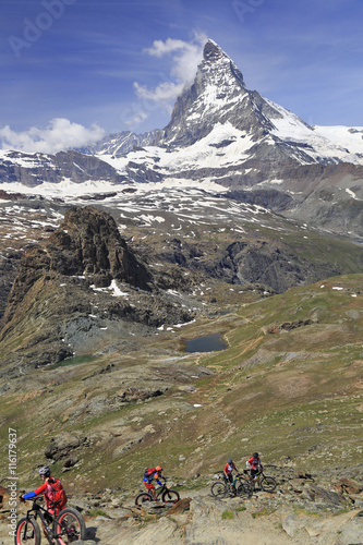  View of Matterhorn and cyclists enjoying the challenge on mountain trails in Switzerland, Europe