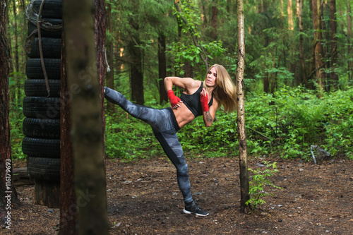 Fit girl beat high leg side kick working out outdoors. Woman fighter exercising  doing kickboxing training martial arts