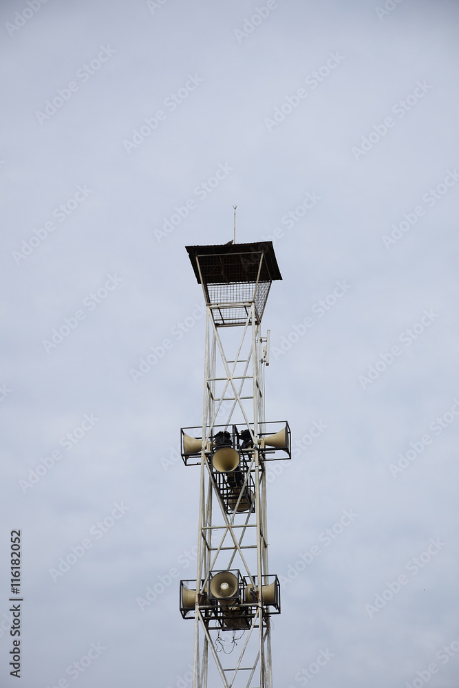 Loudspeakers broadcast tower on sky background.