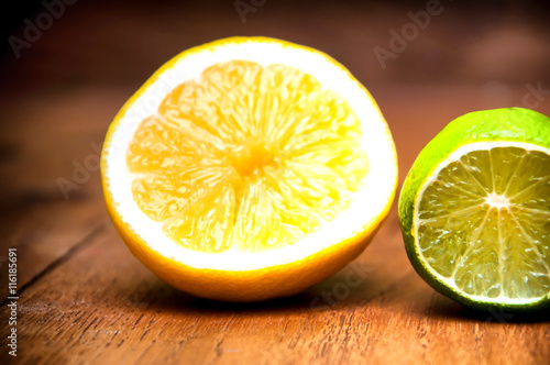 Ripe lemons and limes over black wooden background