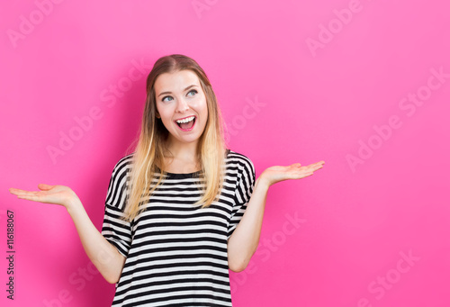 Happy young woman posing on pink background © Tierney