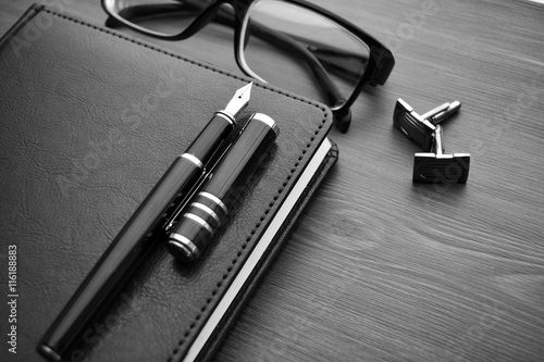 Business accessories on desktop: notebook, diary, fountain pen, cufflinks, glasses.  photo